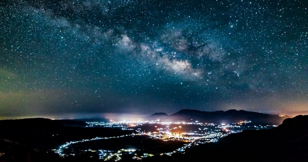 天の川と夜景が輝く都市の風景