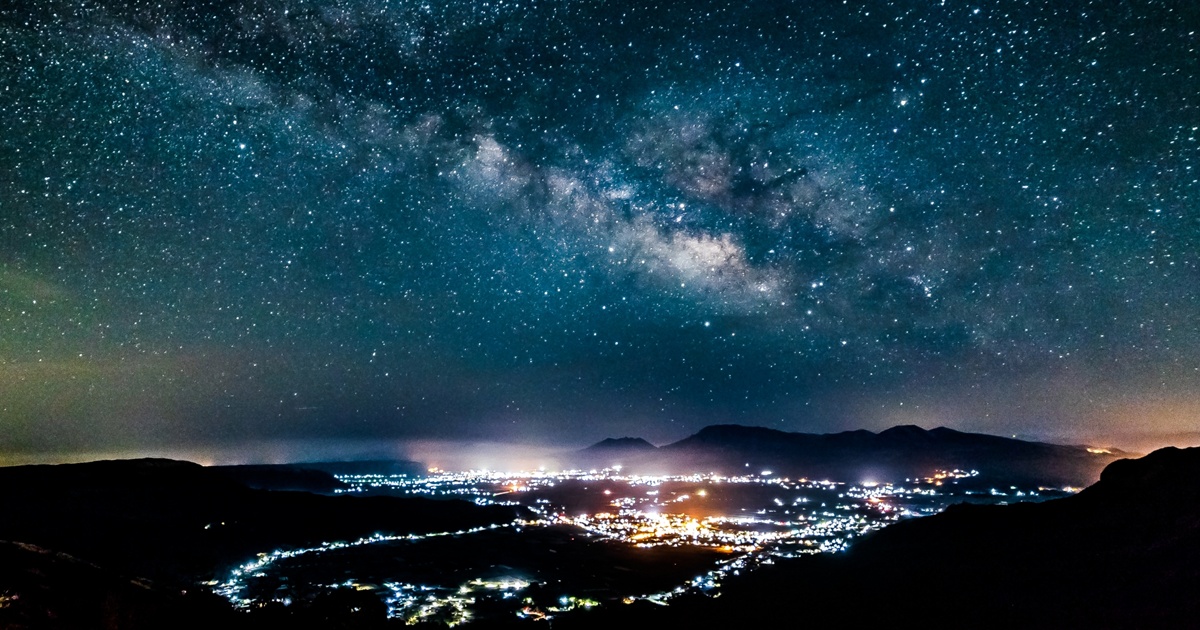 天の川と夜景が輝く都市の風景