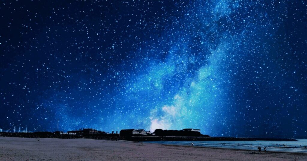 砂浜と海と満天の星空に広がる天の川