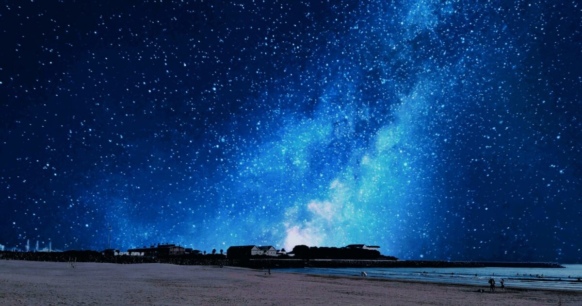 砂浜と海と満天の星空に広がる天の川
