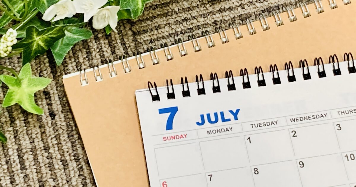 カーペットの上に置かれた7月のカレンダーと観葉植物